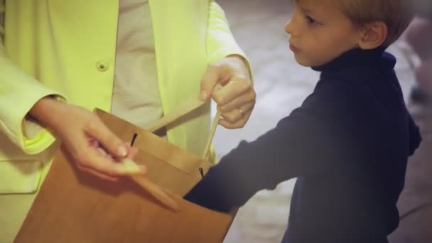 Un niño pequeño con su madre en el mercado. Niño pone mandarinas en una bolsa de papel — Vídeo de stock