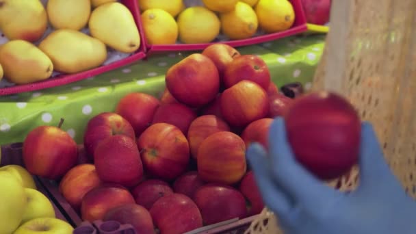 Gros plan de la femme en manteau jaune met des pommes rouges dans un sac à ficelle au marché — Video