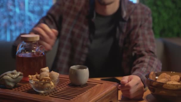 Gros plan du jeune homme boit du thé chinois traditionnel, il verse du thé chaud de la bouilloire à la tasse et le boit au café — Video