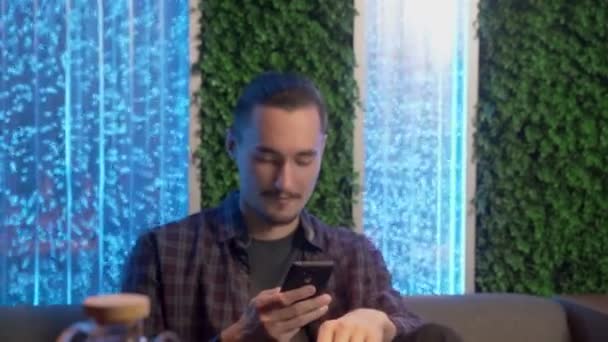 Jeune homme utilise le téléphone dans un café ou un club — Video