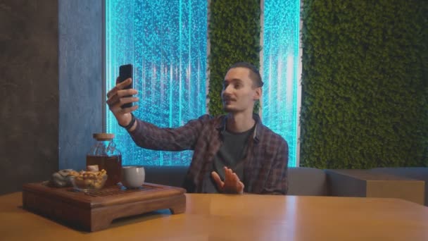 Joven registra historias en su teléfono en la cafetería de té chino — Vídeos de Stock