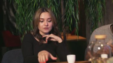 Genç bir kadın kafedeki Afrikalı arkadaşıyla telefonda selfie çekiyor.