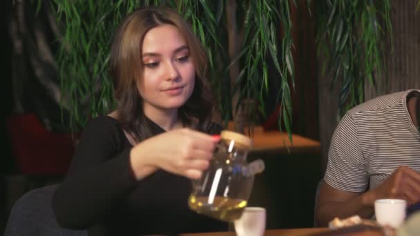 Ung kvinna dricker kinesiskt te och äter kakor på caféet med vänner — Stockvideo