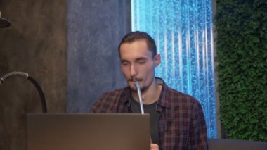 Çekici, neşeli adam defter üzerinde çalışırken bir shisha tüttürür.