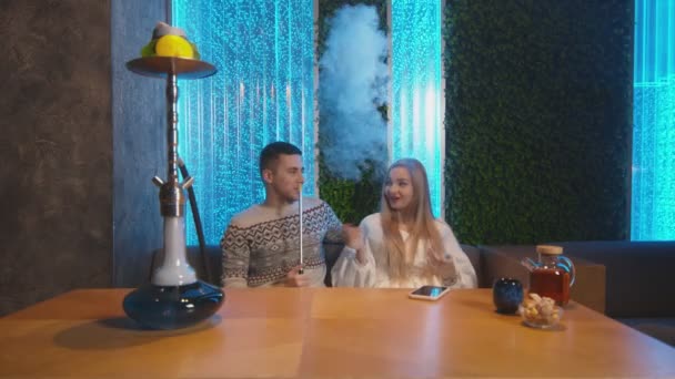 Ung man och kvinna har tid tillsammans och röker i en hora i shisha lounge — Stockvideo