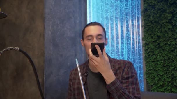 Close-up van vrolijke man in fashion outfit opnemen van een voice message telefoon tijdens het roken van een shisha — Stockvideo