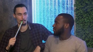 En iyi arkadaşlar shisha barda oturur, sigara içer ve konuşur.