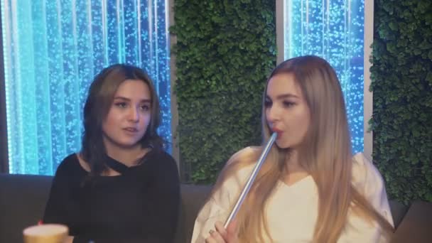 Zblízka dvě kamarádky v baru Hookah. jedna žena nabízí kouření, druhá odmítá a pije čaj — Stock video