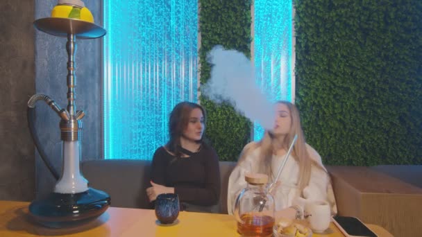 Två kvinnliga vänner i Hookah Bar. en kvinna erbjuder sig att röka, en annan kvinna vägrar och dricker te — Stockvideo