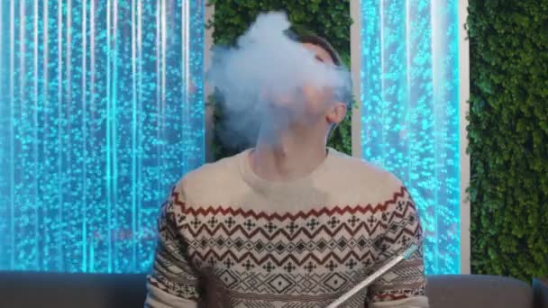 Mladý pohledný muž kouří hookah a dívá se do kamery — Stock video