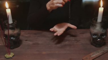 Kadın falcı, sihirli kehanet ritüeli için iplikle iğne kullanır.