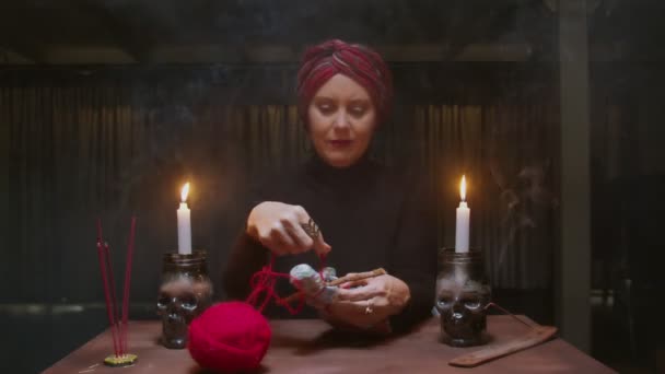 Donna strega anziana indovina utilizza bambola voodoo e corda rossa per terribile rituale magico — Video Stock