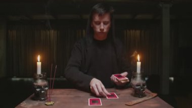Yoğunlaşmış gizemli büyücü erkek falcı mistik ayin olarak kartları yerleştiriyor..