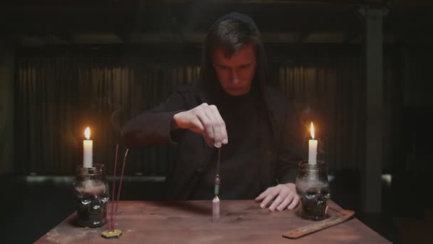 Feiticeiro misterioso concentrado cartomante masculino gira um cristal mágico azul em volta de outro cristal na mesa em ritual místico — Vídeo de Stock