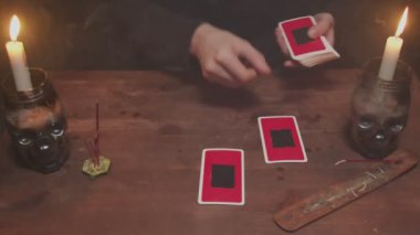 Gizemli büyücü erkek falcıya yakın çekim. Geleceği okumak için tarot kartı ve telefon kullanıyor.