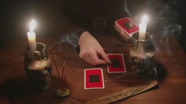 Gizemli büyücü erkek falcıya yakın çekim. Geleceği okumak için tarot kartı ve telefon kullanıyor.