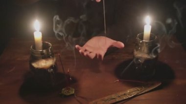 Gizemli büyücü erkek falcıya yakın mesafede sihirli kehanet ritüeli için iplikle iğne kullanıyor.