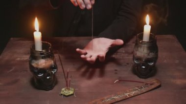 Gizemli büyücü erkek falcıya yakın mesafede sihirli kehanet ritüeli için iplikle iğne kullanıyor.