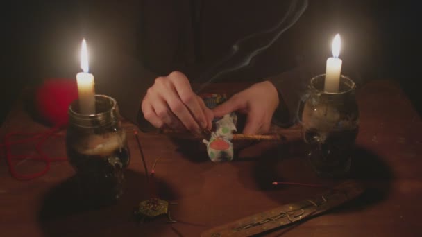 Close up de misterioso feiticeiro cartomante masculino enfia uma agulha na boneca vodu em terrível ritual mágico no escuro — Vídeo de Stock