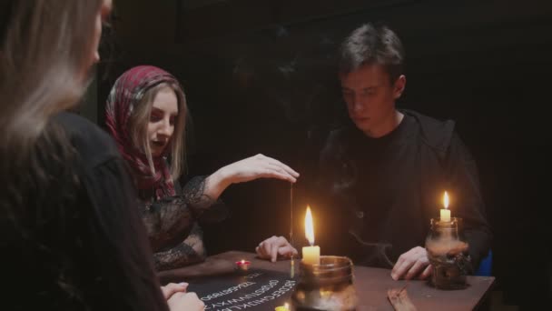 Hexe Wahrsagerin versucht, mit Geist zu sprechen. Zwei Frauen und ein Mann nutzen Ouija Brettspiel — Stockvideo