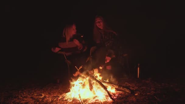 Дві молодої жінки з багаттям у лісі, вони готують зефір — стокове відео