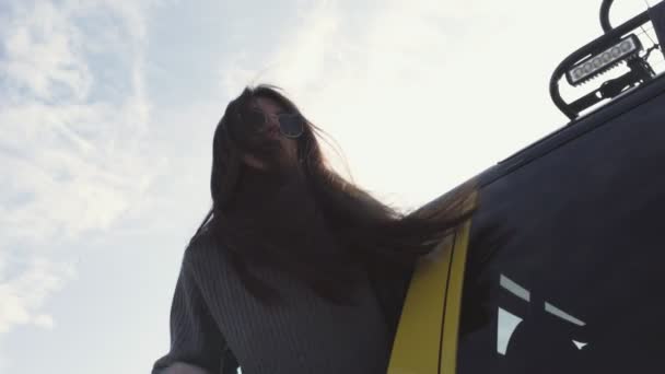 Młoda kobieta w okularach przeciwsłonecznych wychylona przez okno samochodu — Wideo stockowe