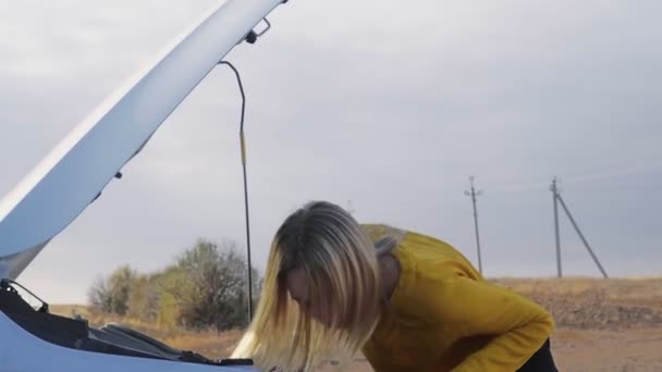 Kobieta próbuje naprawić silnik, młoda zdenerwowana kobieta stoi w zepsutym samochodzie martwiąc się w stresie. — Wideo stockowe