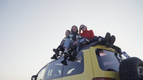 Três as melhores namoradas senta-se no carro amarelo ao ar livre e posa na câmera — Vídeo de Stock