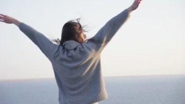 Dışarıda kameraya poz veren süveterli ve güneş gözlüklü güzel bir kadın.