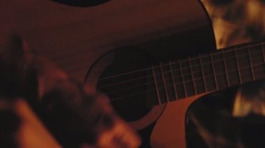 Geceleri ateş yakan bir adam gitar çalıyor.