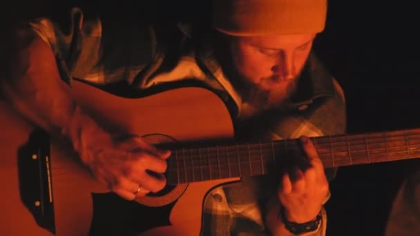 Close up de homem barbudo toca guitarra perto de fogueira à noite — Vídeo de Stock