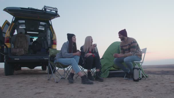 Jonge gelukkige vrienden kampeerders zitten naast de tent en de auto en praat — Stockvideo