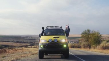 Sürücü arabasından sarkan güneş gözlüklü genç kadın.