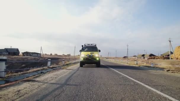 Přední pohled na žluté karavany van vyjíždí na prázdné silnici — Stock video