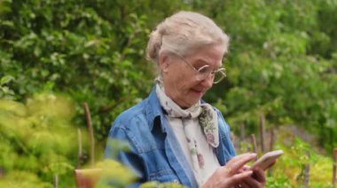 Yeşil yaz parkında cep telefonuna bakan mutlu son sınıf öğrencisi kadın.