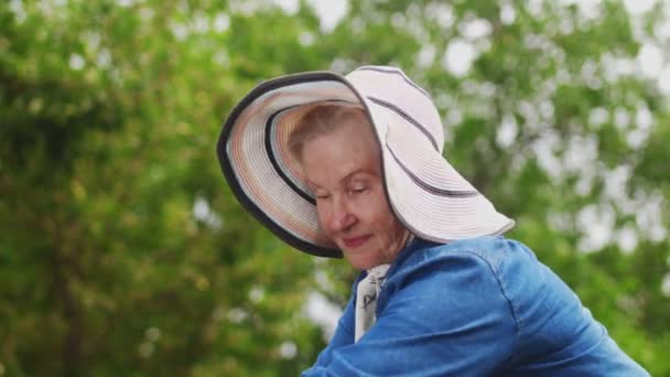 Zbliżenie babci w białym kapeluszu Podlewanie Rośliny w ogrodzie — Wideo stockowe