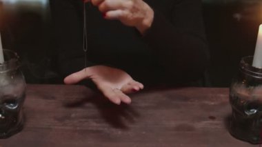 Kadın falcı, sihirli kehanet ritüeli için iplikle iğne kullanır.