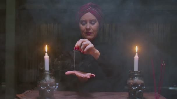 シニア女性占い師は魔法の占いの儀式に糸で針を使用しています — ストック動画