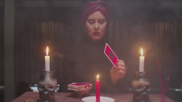 Старшая ведьма-гадалка передвигает карту Таро через свечи и говорит будущее в магическом ритуале — стоковое видео