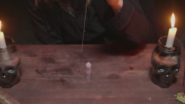 Genç cadı kadın falcı mistik ritüelde iğneyi masanın etrafında döndürür.