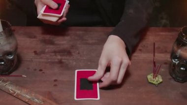 Gizemli büyücü erkek falcıya yakın çekim. Geleceği okumak için tarot kartı ve telefon kullanıyor.