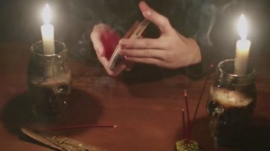 Gizemli büyücü erkek falcıya yakın çekim yap. Kartları karıştır ve onları geleceğe dair bilgilere hazırla.