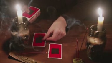 Gizemli büyücü erkek falcıya yakın çekim. Geleceği okumak için tarot kartı ve telefon kullanıyor.