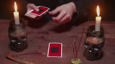 Gizemli büyücü erkek falcıya yakın çekim. Geleceği okumak için tarot kartı ve telefon kullanıyor.