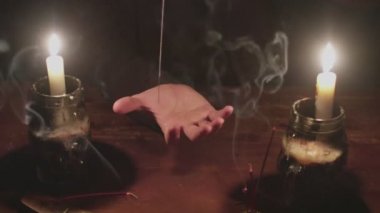 Gizemli büyücü erkek falcıya yakın mesafede sihirli kehanet ritüeli için iplikle iğne kullanıyor.