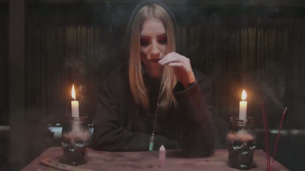 Jovem bruxa cartomante gira um cristal mágico azul em volta de outro cristal na mesa em ritual místico — Vídeo de Stock