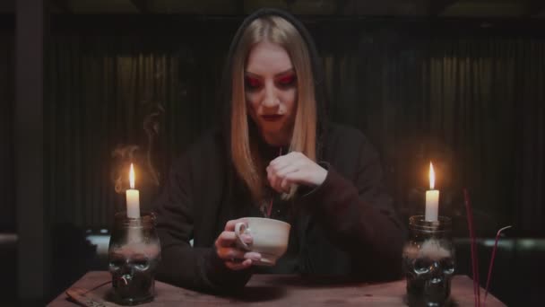 Young witch female fortune teller is holding coffee cup and reading fate — Stock Video