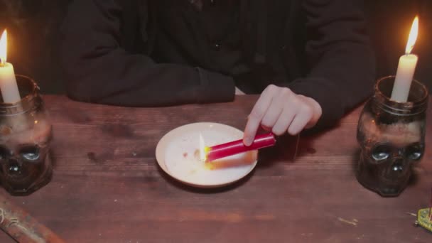 Κοντινό πλάνο της νεαρής μάγισσας γυναίκα μάντισσα κρατά κερί που στάζει κερί σε ένα πιάτο για να κάνει σταυρό σε τρομερό τελετουργικό μαγεία — Αρχείο Βίντεο