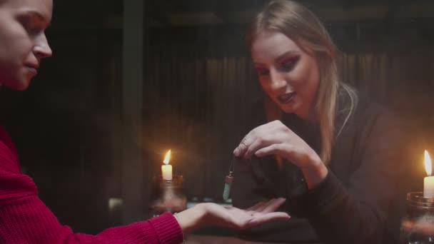 Молодая ведьма-гадалка использует голубой магический кристалл, чтобы предсказать будущее своему молодому клиенту — стоковое видео