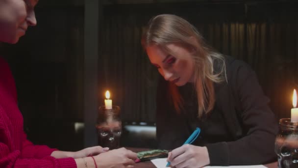 Tânăra vrăjitoare femeie ghicitoare scrie clienților răspunsuri la numerologie avere spune magie — Videoclip de stoc